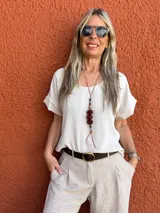 Blusa color beige de seda opaca, con cuello redondo y mangas cortas.