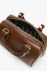 Bolso marrón formato city con asa doble de mano con detalles metálicos y correa interior extraíble en tejido canvas con posición bandolera. Bolsillo interior con cierre mediante cremallera metálica.