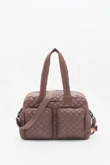 Bolso marrón con diseño matelassé, doble asa corta, correa larga desmontable y dos bolsillos frontales. Incluye llavero de corazón y dijes desmontables.