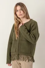 Chaqueta corta color gris oscuro confeccionada en lana merino hervida, con cuello redondo, mangas largas y bolsillos frontales. Presenta detalle de flecos en el ruedo.