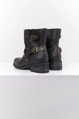 Bota de caña corta en cuero negro craquelado, con base de madera y herrajes en color oro viejo.