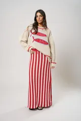 Sweater tejido color crudo con cuello redondo y mangas largas. Presenta dos peces rojos con detalles en azul bordados en el frente. Tiene ribete ondulado rojo en cuello, puños y ruedo.