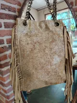 Bolso tipo bandolera color dorado con flecos y cadena metálica.
