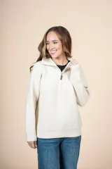 Cardigan color crudo de tejido de punto acanalado, con cuello alto y cierre frontal parcial con cremallera metálica. De corte oversize, mangas largas y puños ajustados.