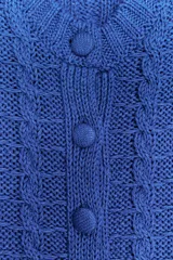 Chaqueta de punto azul con cuello redondo y manga corta. Cierre frontal con botones forrados y diseño en relieve.