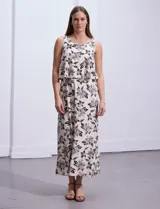 Vestido largo de seda fría color beige con estampado floral en negro. Tiene escote redondo con sobrecapa y corte en la cintura con punto smock.