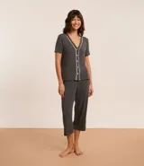 Conjunto de pijama gris oscuro confeccionado en viscosa, compuesto por una camisa de manga corta con cuello en V, abotonada adelante y detalle contrastante blanco; y un pantalón capri con cintura elástica.
