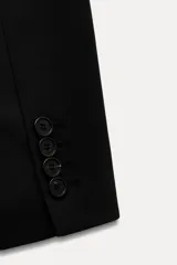 Blazer recta negra de Zara Woman Collection, con cuello solapa, manga larga con abertura y botones, bolsillos de plastrón en delantero, forro interior a tono y cierre frontal con botones.