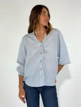 Camisa celeste de lino con mangas 3/4 abullonadas y cuello en V con volados.