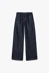 Pantalón de jean azul oscuro, de tiro medio, corte ancho y largo, estilo jogger con cintura elástica ajustable con cordones, bolsillos delanteros de vivo y bolsillos de parche en la espalda.