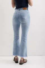 Pantalón jean marrón acampanado con detalle desflecado en el bajo y tiro medio.