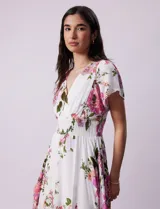 Vestido blanco con estampado floral en tonos rosados, violetas y verdes. Escote en V tanto en la parte delantera como en la espalda. Cintura elastizada con punto smock y forro interno a tono.