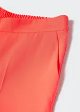 Pantalón de traje de corte wideleg color coral, de tejido fluido con forro interior y elástico en la parte posterior de la cintura. Presenta dos bolsillos laterales y cierre oculto de botón, gancho y cremallera.