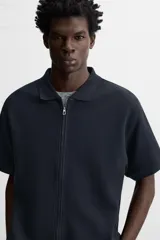 Chaqueta azul marino de tejido con mezcla de algodón, corte relaxed fit, cuello solapa, manga corta y cierre frontal con cremallera.
