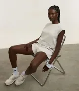 Bermuda deportiva color gris claro, confeccionada en microfibra acanalada, de corte holgado y largo a medio muslo.