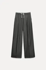 Pantalón ancho gris con textura de espiga, tiro alto, doble cintura elástica ajustable con cordón, pinzas frontales, bolsillos delanteros y falso bolsillo de vivo en la espalda.
