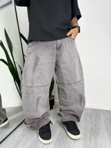 Pantalón gris de denim con corte holgado y efecto lavado. Incluye cadena metálica como accesorio.