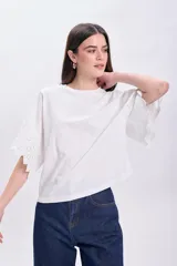 Remera blanca de algodón con mangas cortas y detalle de broderie calada en los bordes.