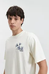 Remera color crudo de manga corta con cuello redondo y estampado en la espalda con flores azules y texto.