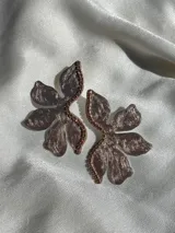 Par de aros con forma de flor roja brillante y detalle de strass plateado en el centro. Cierre a presión de acero inoxidable.