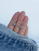 Aritos colgantes plateados con forma de corazón y strass azules.