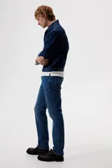 Pantalón de jean de corte recto, color azul medio, con cinco bolsillos y cierre con botón y cremallera. Confeccionado en denim de algodón con leve stretch.