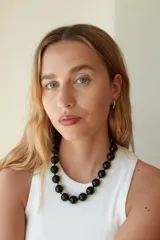 Collar de cuentas esféricas grandes de acrílico blanco, ensartadas en un cordón claro.