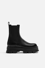 Bota Chelsea de cuero negro con elásticos laterales, tirador trasero y suela track de goma.
