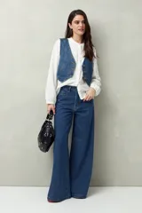 Pantalón de jean negro de calce ultra wide leg, tiro alto y silueta amplia desde la cadera hasta el bajo. Diseño clásico de cinco bolsillos y cierre con botón metálico y cremallera.
