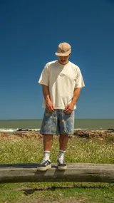 Remera boxy de algodón color beige con parche con logo en el pecho. Corte más corto de lo normal, ideal para combinar con pantalones y bermudas baggy, anchos o rectos.