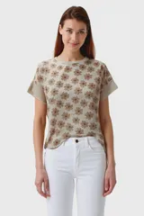 Remera color beige con estampado de flores marrones, corte recto y mangas cortas con detalle de doblez.