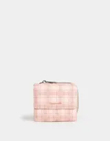 Billetera de cuerina color rosa con estampado escocés, solapa con broche y tag metálico.