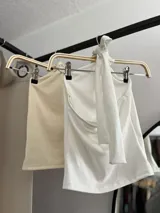 Top blanco de estilo halter con aro metálico en el cuello.