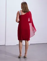 Vestido de fiesta azul marino de seda fría, corte a la rodilla, con un hombro descubierto y aplique de lentejuelas plateadas en el bretel. Incluye una capa de gasa transparente que se sujeta al hombro.