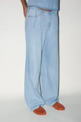 Pantalón denim celeste de tiro medio con cintura ajustable con cordones, bolsillos laterales y de plastrón en espalda. Cierre frontal con cremallera y gancho metálico.