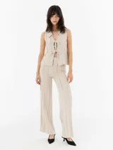 Pantalón de lino color beige, de corte recto y tiro alto, con detalle de flecos verticales.