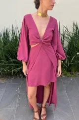 Vestido largo color borgoña, con escote en V, mangas largas abullonadas y falda con volados. Presenta un corte en la cintura con detalle de nudo.