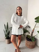 Vestido corto tejido al crochet color blanco, con mangas largas y escote redondo con borde negro.