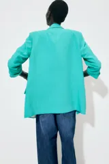 Blazer marrón con cuello solapa y hombreras. Manga tres cuartos con trabilla y botón dorado. Bolsillos delanteros con solapa.