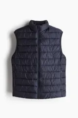 Chaleco puffer azul marino con cuello alto, cierre frontal y bolsillos laterales con cierre. Corte ajustado. Sin mangas.