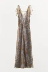 Vestido largo de gasa color celeste con estampado floral color dorado, escote fluido, mangas cortas con abertura, detalle de frunce en el delantero y espalda con escote pronunciado. Incluye forro interior de tirantes al tono.