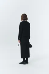 Chaqueta corta negra de lana con cuello redondo, botones metálicos plateados y bolsillos frontales con solapa.