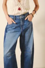 Pantalón jean de tiro alto, corte amplio y pierna ancha con parches en diferentes tonos de azul.