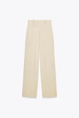 Pantalón de tiro alto color beige confeccionado con lino, de pierna recta, con bolsillos delanteros y falsos bolsillos de vivo en la espalda.