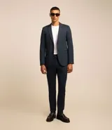 Pantalón de traje de corte super slim, color azul oscuro, confeccionado en tejido de poliviscosa con textura discreta. Presenta trabillas en la cintura, cierre de cremallera y botón, y bolsillos laterales y traseros.