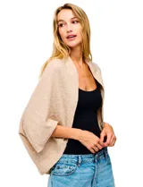 Cardigan negro de tejido suave, estilo poncho o capa, con cuello tipo chal y mangas amplias.