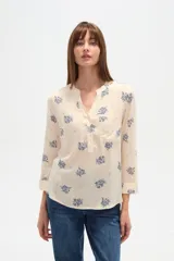 Blusa de manga tres cuartos color crema con estampado floral en azul. Presenta cuello mao con abertura en V y un bolsillo de parche en el pecho.