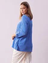 Camisa celeste de textura arrugada, con cuello clásico, cierre frontal con botones y mangas 3/4 con trabilla.