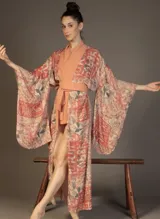 Kimono largo con mangas amplias, estampado floral y motivos orientales en tonos coral, rosado pálido y verde grisáceo. Presenta un fajín ancho y un cuello solapa en color salmón liso.