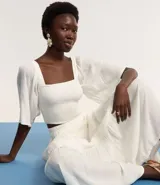 Blusa cropped color blanco, con escote recto, mangas amplias con elástico en los hombros, lastex en el cuerpo y textura.